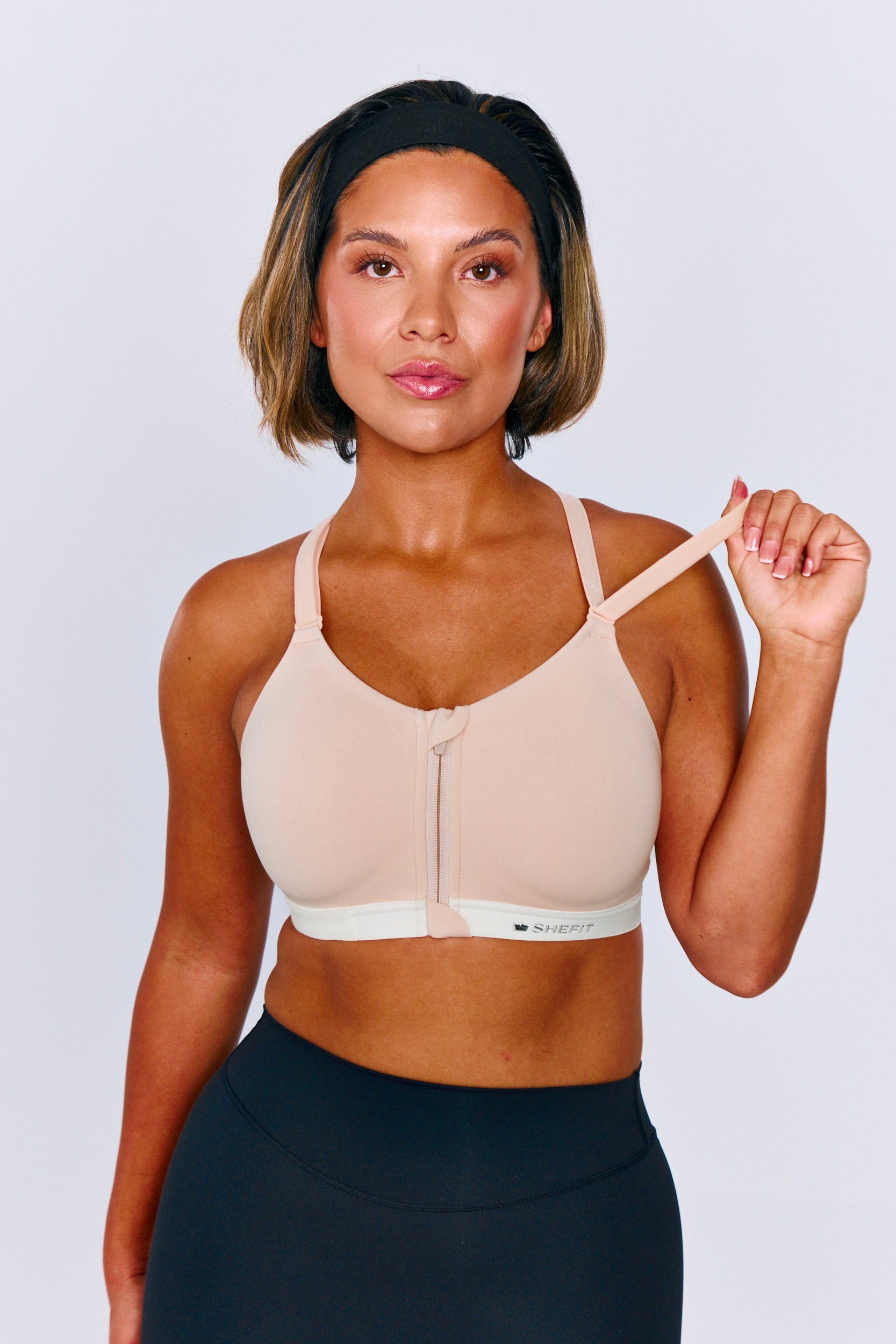 Model wearing a SHEFIT zip-front sports bra and adjusting the strap.